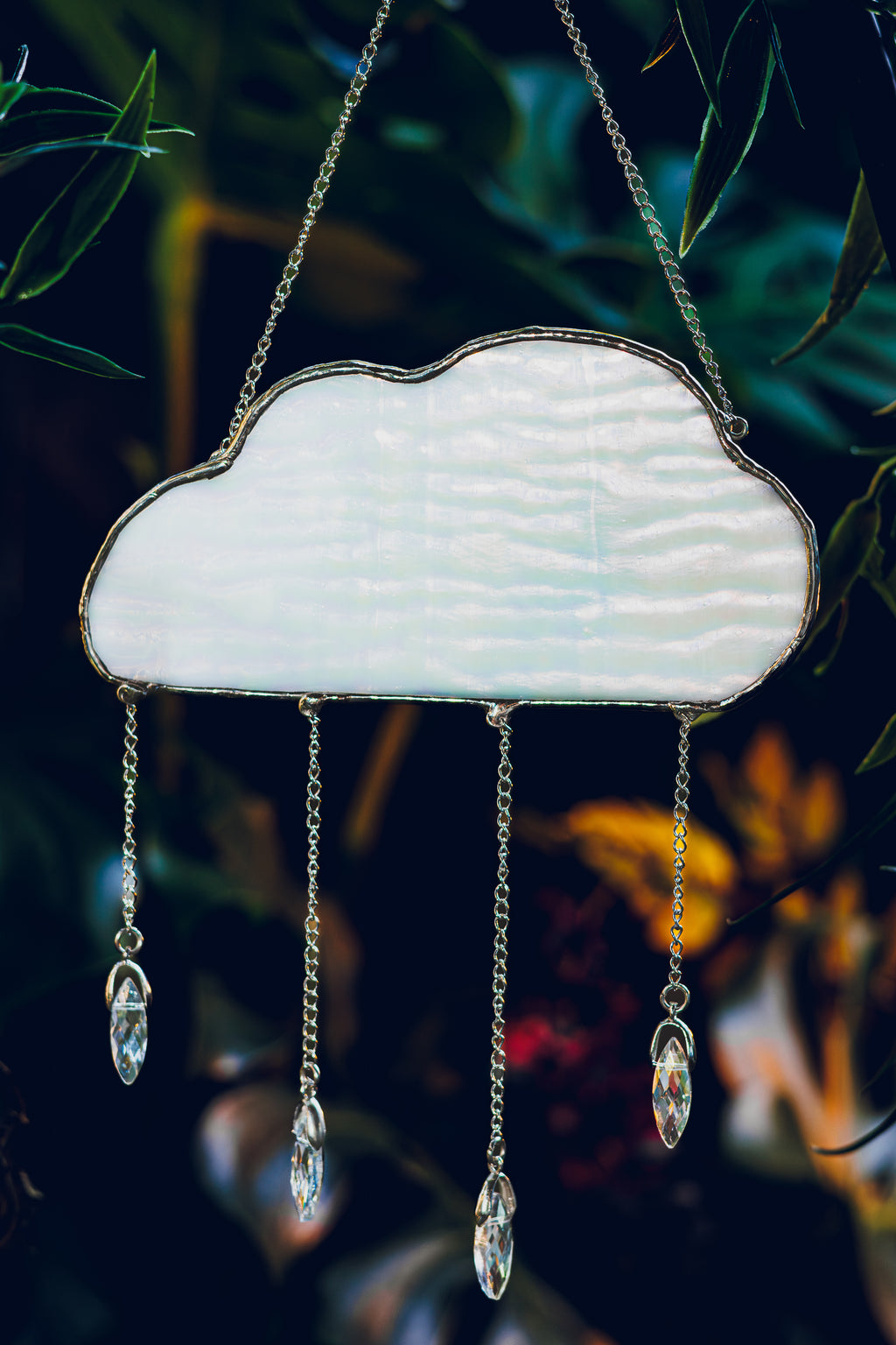 Decorative cloud-shaped stained glass with crystal-like droplets against a dark background