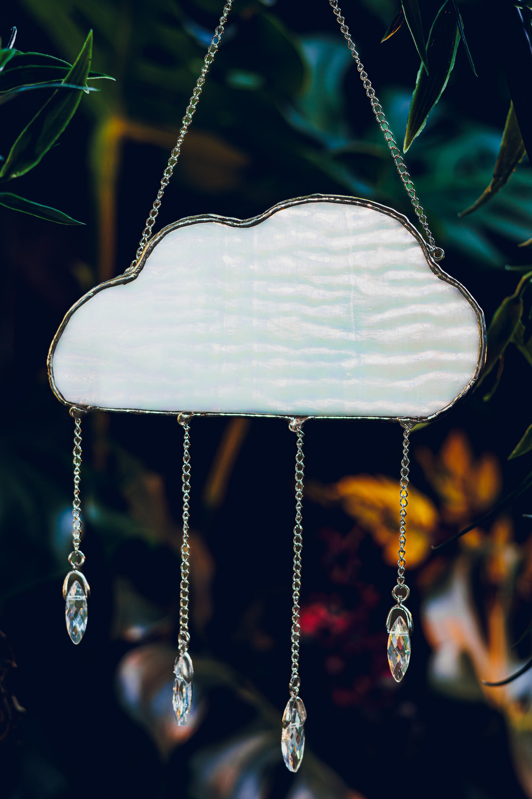 Decorative cloud-shaped stained glass with crystal-like droplets against a dark background
