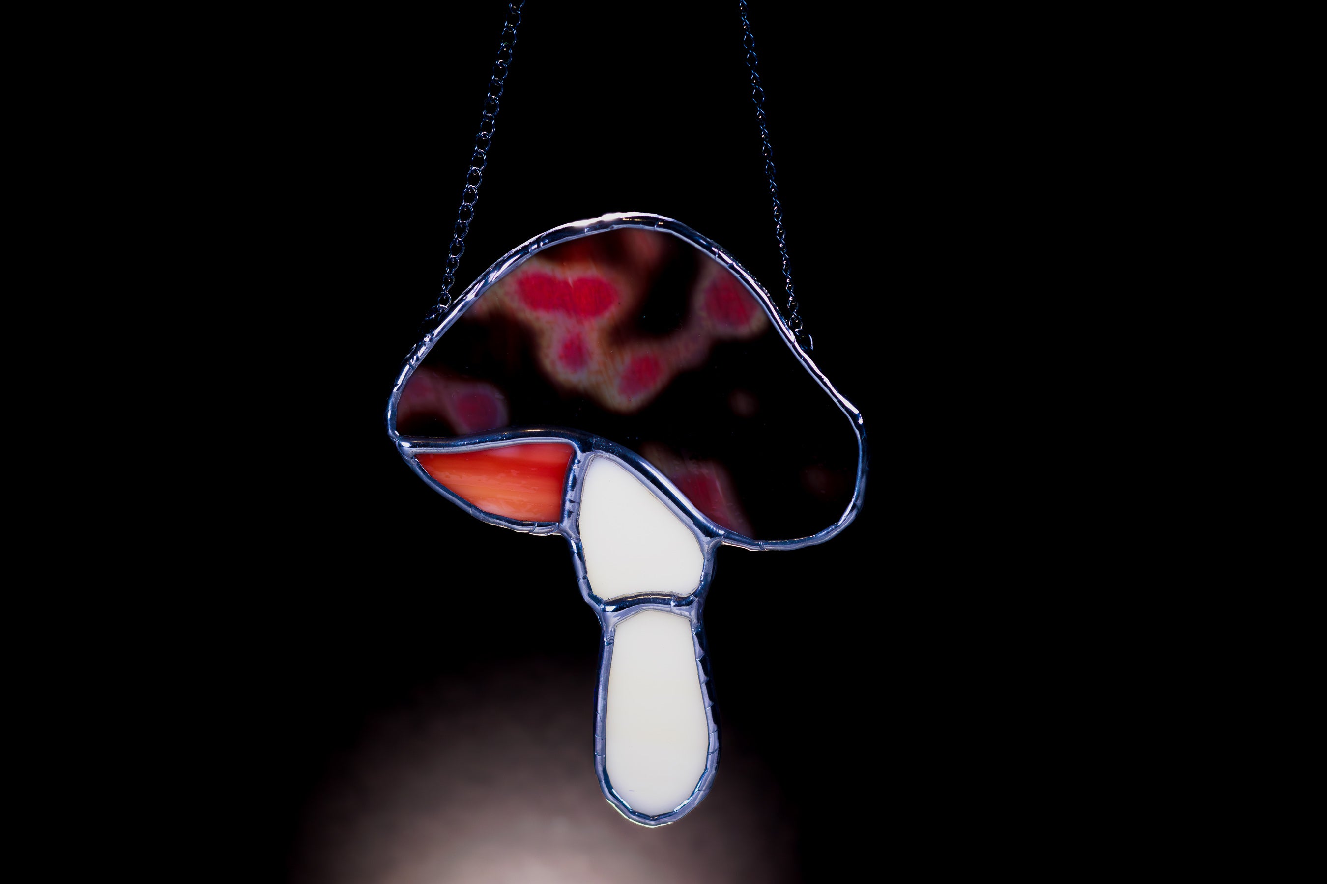 Stained glass mushroom pendant on a black background